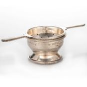 AN ART DECO STYLE SILVER TEA STRAINER ON STAND