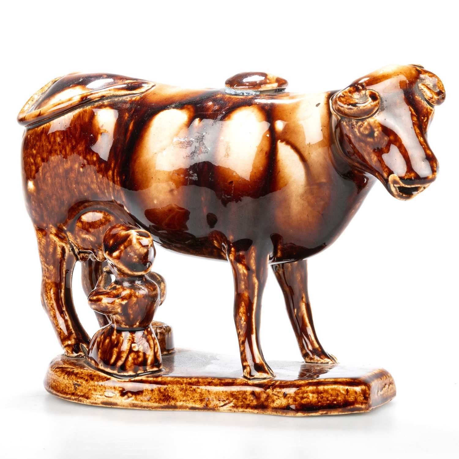 A 19TH CENTURY STAFFORDSHIRE TREACLE-GLAZED POTTERY COW CREAMER AND MILKMAID GROUP