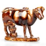 A 19TH CENTURY STAFFORDSHIRE TREACLE-GLAZED POTTERY COW CREAMER AND MILKMAID GROUP