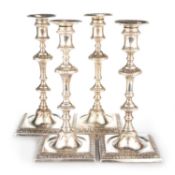 A SET OF FOUR GEORGE III CAST SILVER CANDLESTICKS