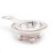 A NEOCLASSICAL-STYLE GERMAN SILVER TEA STRAINER ON STAND