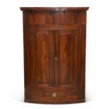 A LARGE REGENCY MAHOGANY BOW-FRONT HANGING CORNER CUPBOARD