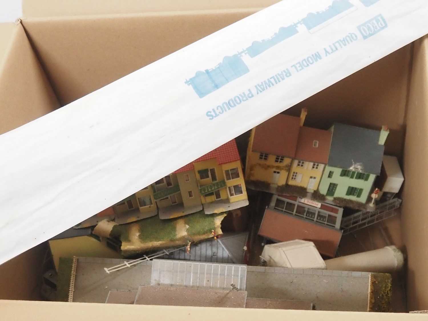 A box of kitbuilt HO gauge plastic buildings by various manufacturers together with a small pack