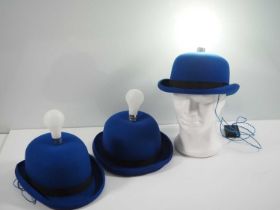 A group of three light-up bulb blue bowler hats by milliners Denton Hats, as worn during the
