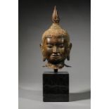 Tête de Buddha au large faciès coiffé de fines bouclettes hérissées, surmonté de la protubérance