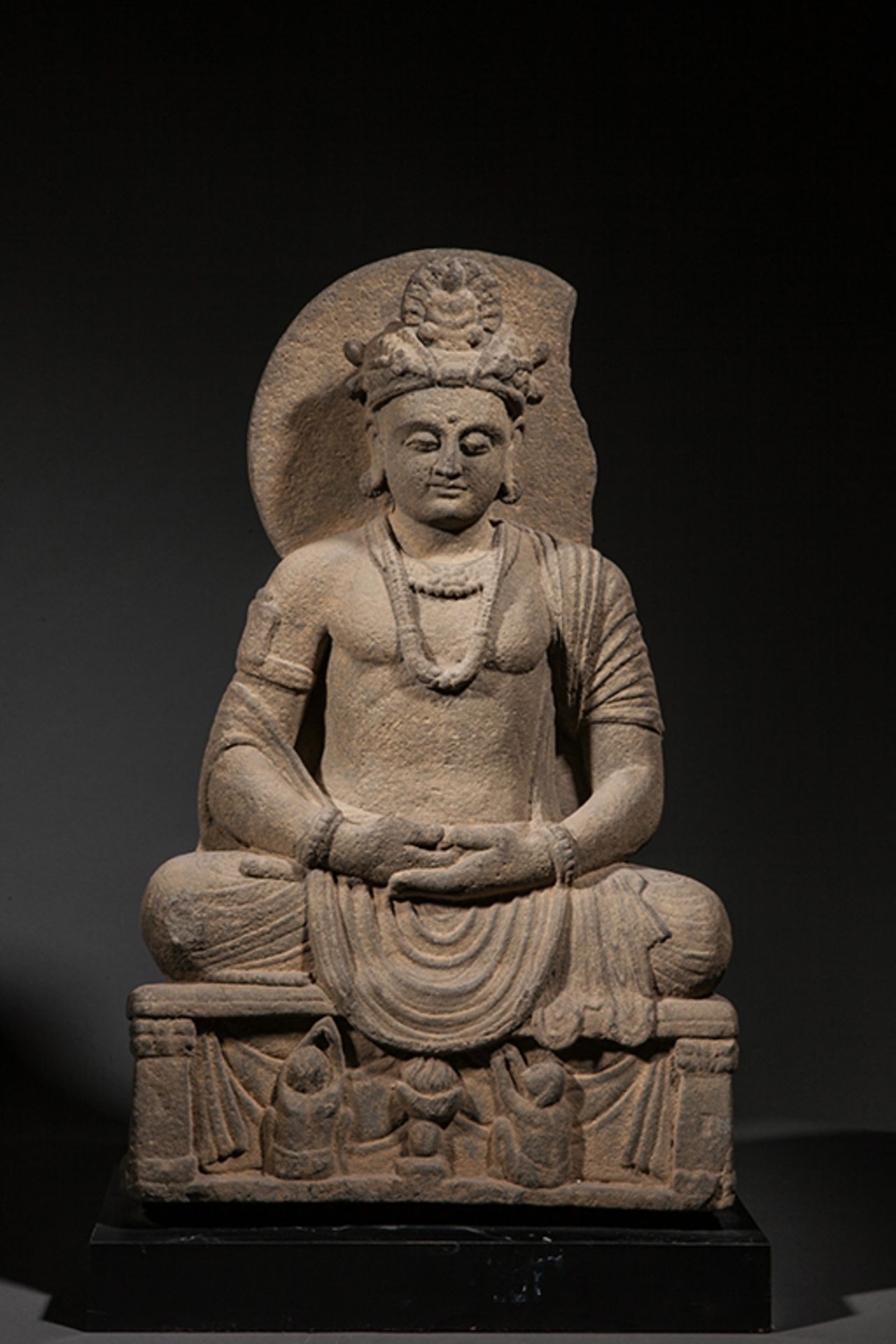 Le Boddhisattva Maïtreya assis en méditation sur un socle habité de deux adorants et d'une