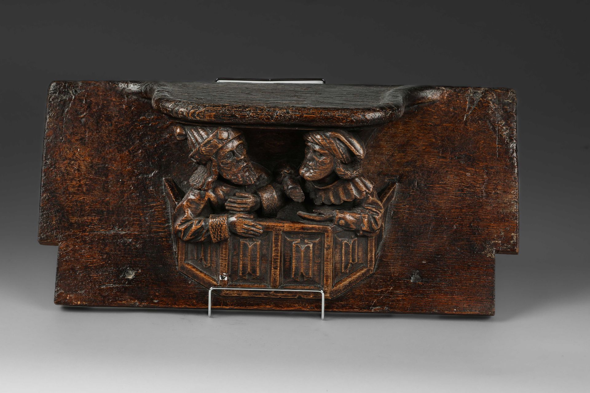 Miséricorde, petit siège mobile incliné avec un rebord surélevé au-dessus de deux figures masculines