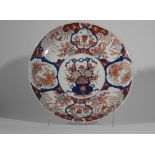 Plat en porcelaine imari décoré en émaux ocre rouge bleu et or sur couverte blanche d'un panier