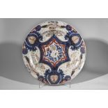 Plat en porcelaine imari décoré en émaux ocre rouge bleu et or sur couverte blanche d'un bouquet