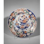 Plat en porcelaine imari décoré en émaux ocre rouge bleu et or sur couverte blanche d'un bouquet