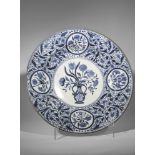 Large plat en porcelaine blanche décorée en bleu cobalt sous couverte d'un vase fleuri au centre