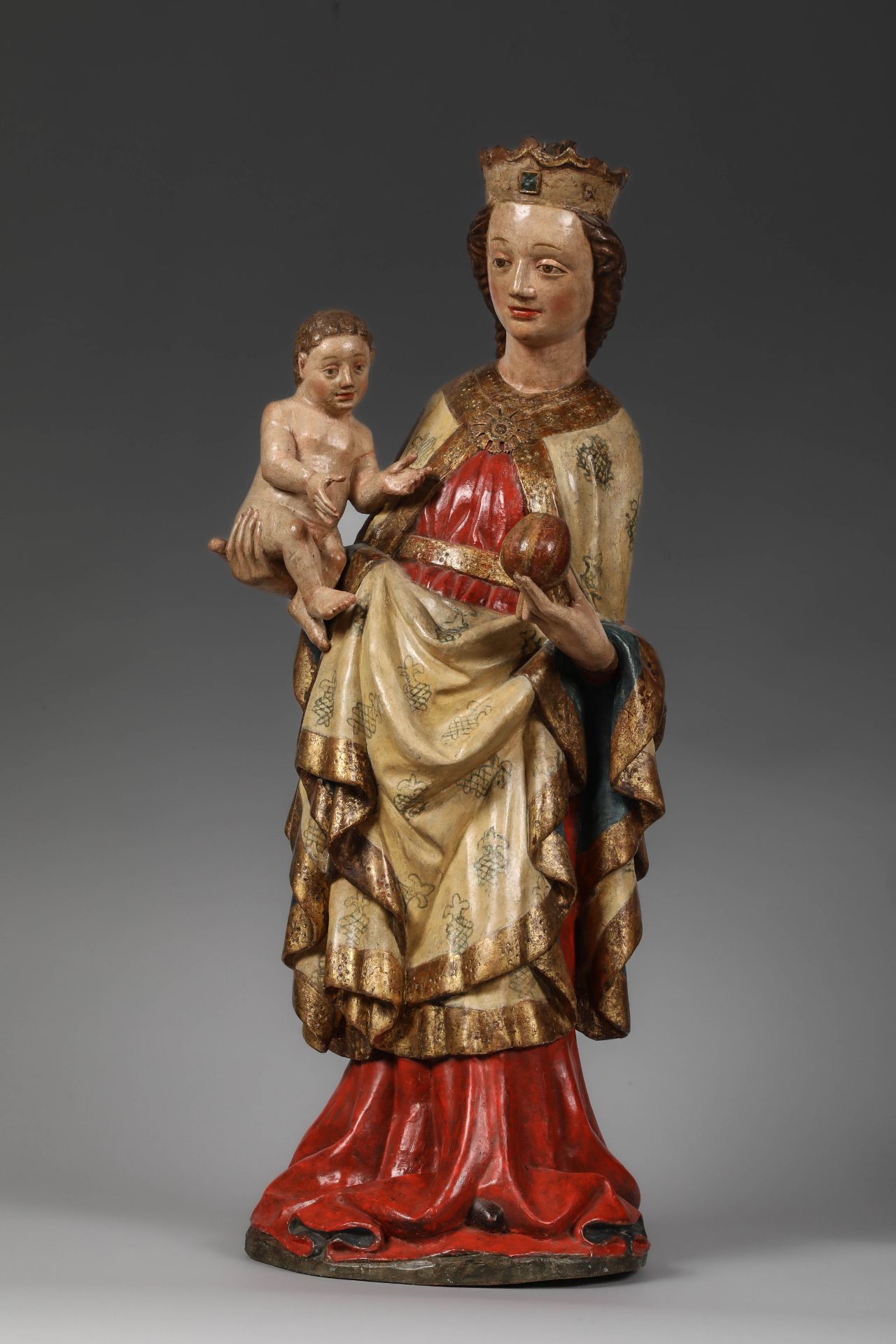 Vierge à l'Enfant vêtue d' une longue robe nouée à la taille et d' un manteau richement brodé retenu
