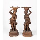 A pair of carved wood figures holding a tray