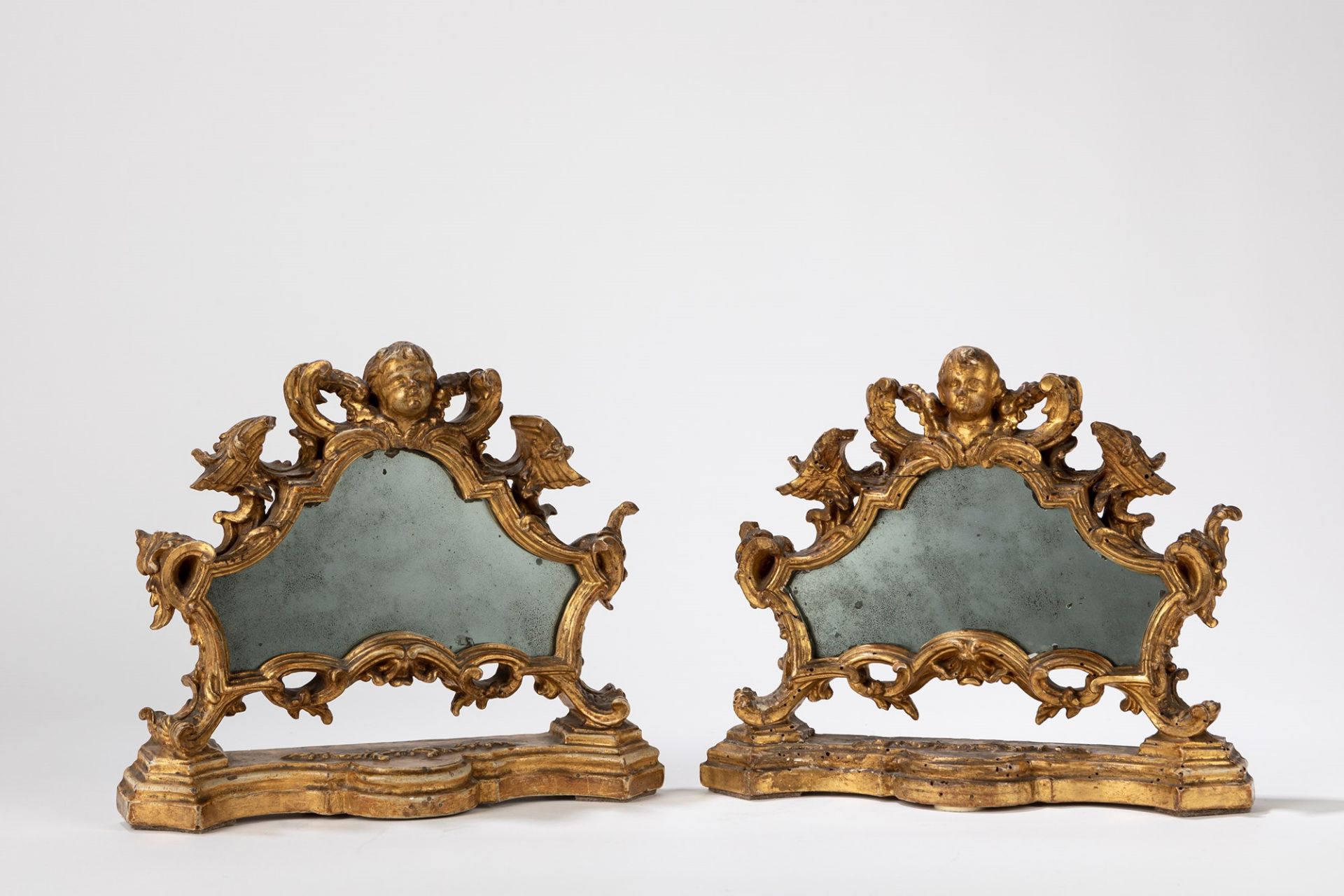 A pair of carved and gilt wood cartaglorias, mounted with mirrors