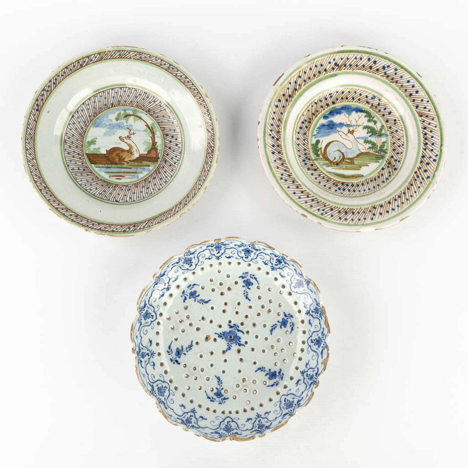 Three pieces of Delfts Faience, two plates with deer and a strainer. 18th C. (D:23 cm)