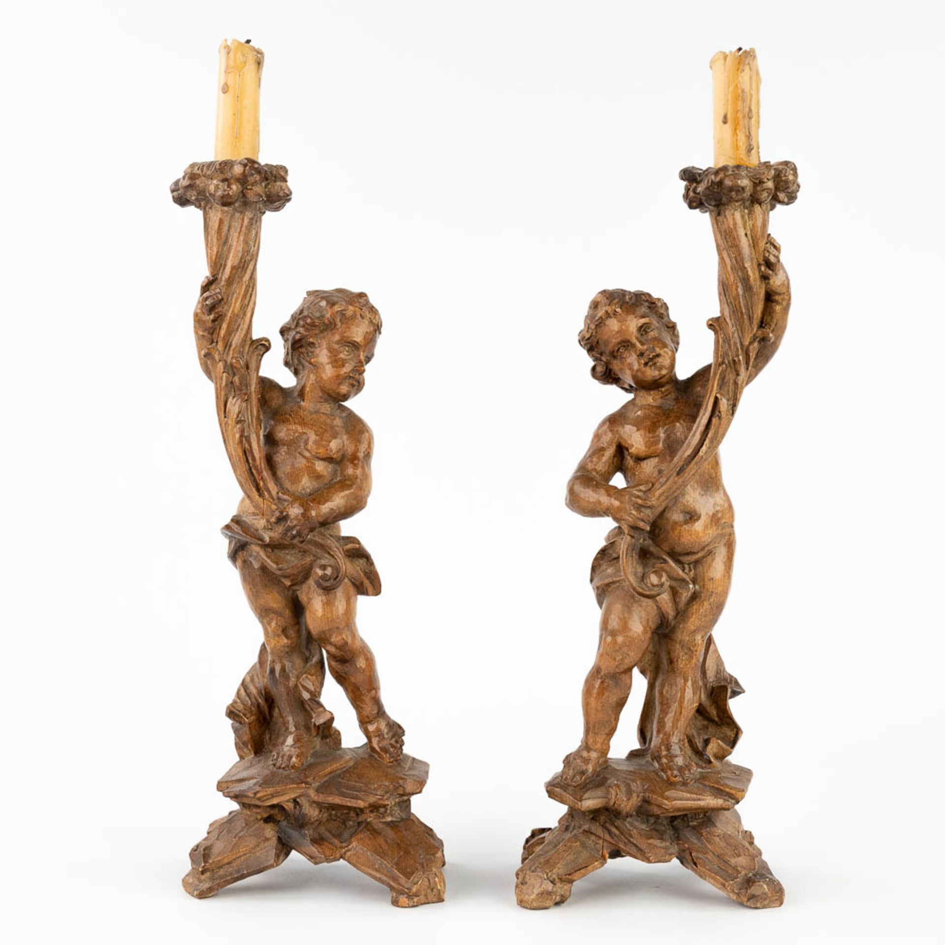 A pair of wood-sculptured candle holders, with putti. 19th C. (L:9 x W:12 x H:34 cm)