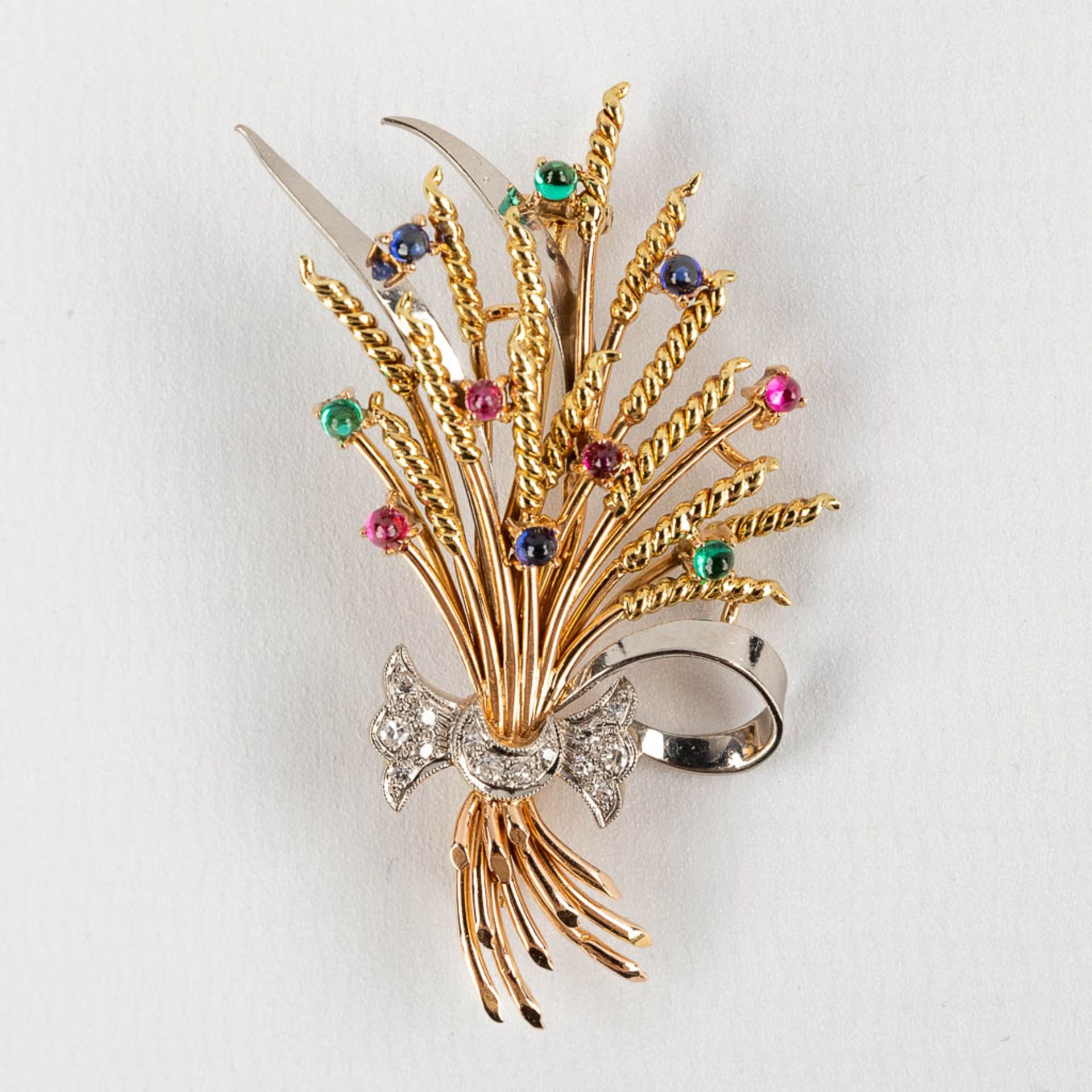 A brooch in the shape of a stack of wheat, with glass cabochons and facetted diamonds. 18kt gold, 13