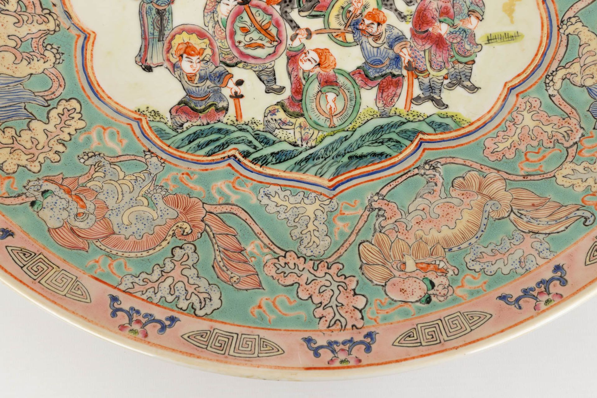 A Chinese Famille Rose plate, decorated with warriors, peaches and Foo Dogs. 19th/20th C. (D:45,5 cm - Image 10 of 13