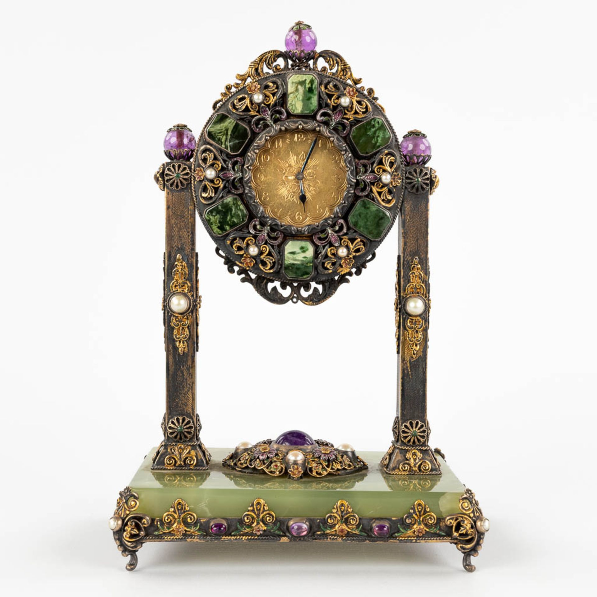 A mantle clock, silver and gold-plated metal and decorated with stone and onyx, pearls. Circa 1900.