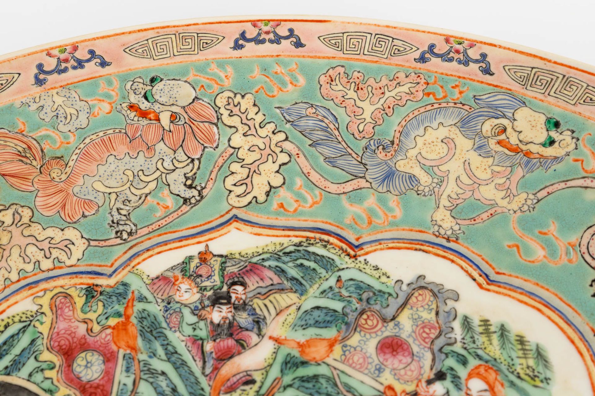 A Chinese Famille Rose plate, decorated with warriors, peaches and Foo Dogs. 19th/20th C. (D:45,5 cm - Image 9 of 13
