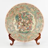 A Chinese Famille Rose plate, decorated with warriors, peaches and Foo Dogs. 19th/20th C. (D:45,5 cm