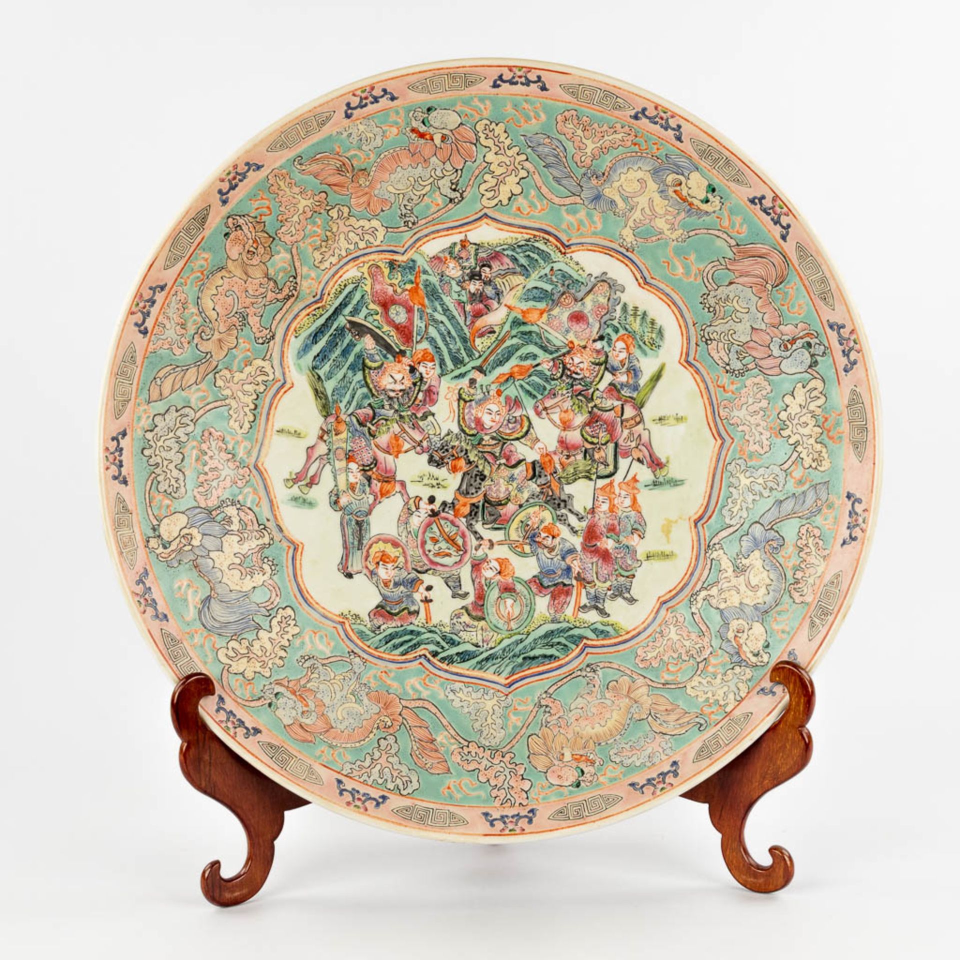 A Chinese Famille Rose plate, decorated with warriors, peaches and Foo Dogs. 19th/20th C. (D:45,5 cm