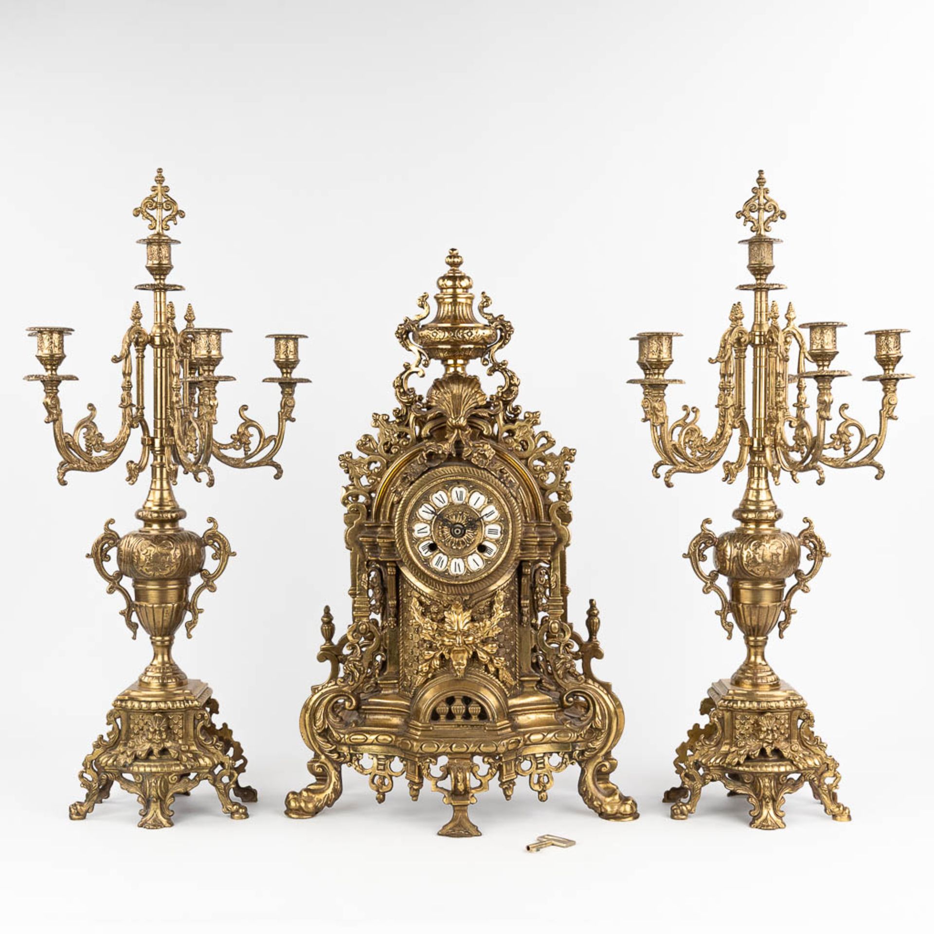 A three-piece mantle garniture consisting of a clock with candelabra, made of bronze. circa 1970. (W