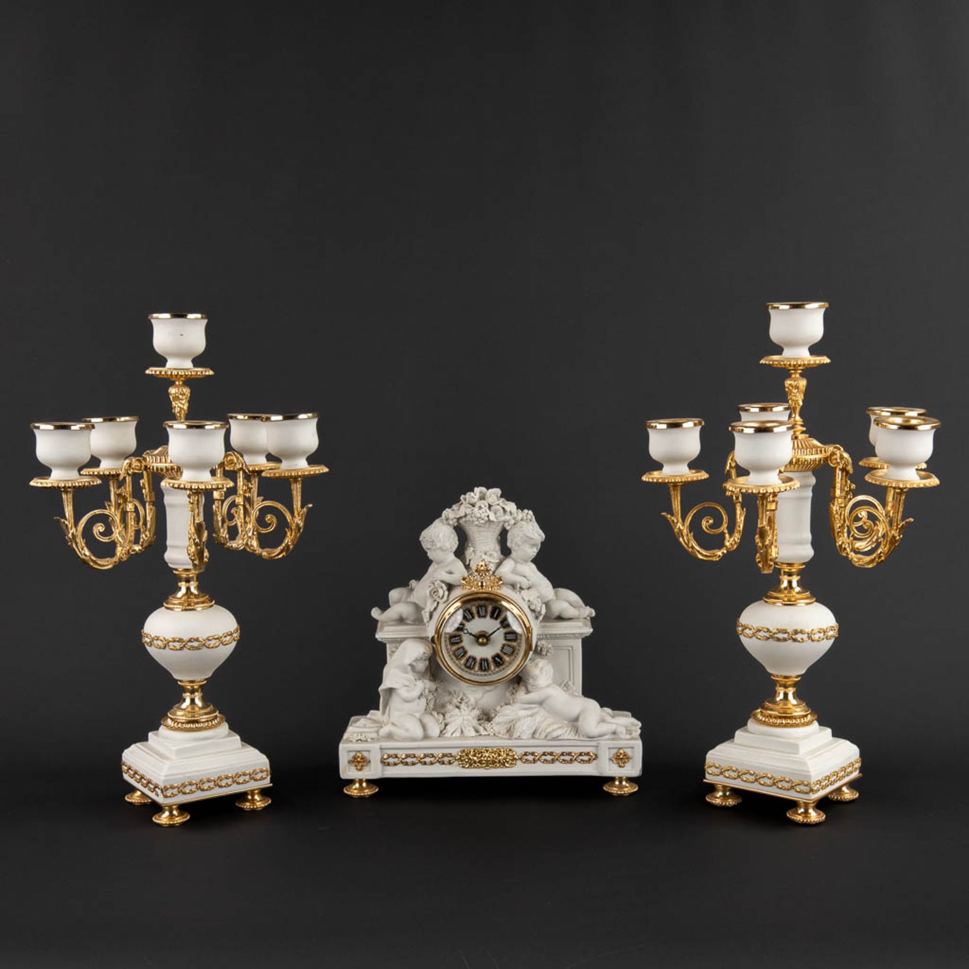 A three piece mantle garniture clock and candelabra, bisque porcelain, 20th C. (D:11 x W:25 x H:26 c