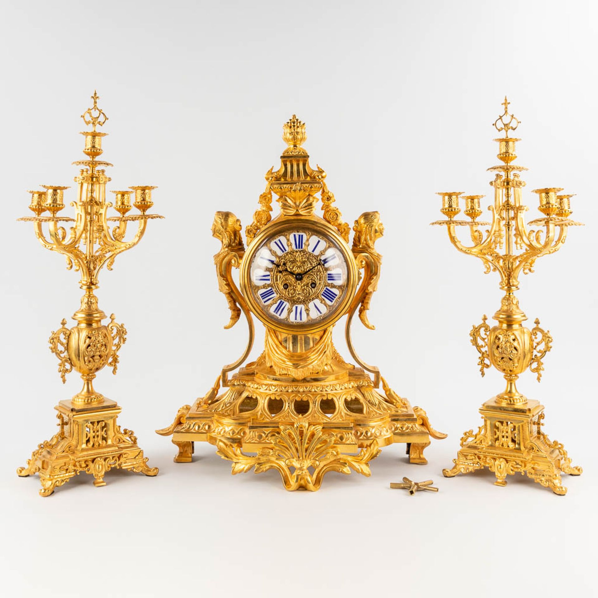 A three-piece mantle garniture clock and candelabra, gilt bronze in Louis XV style. 19th C. (D:28 x