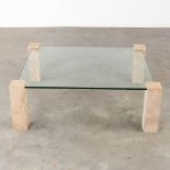 A coffee table with travertine legs, glass top. Circa 1980. (D:105 x W:105 x H:36 cm)