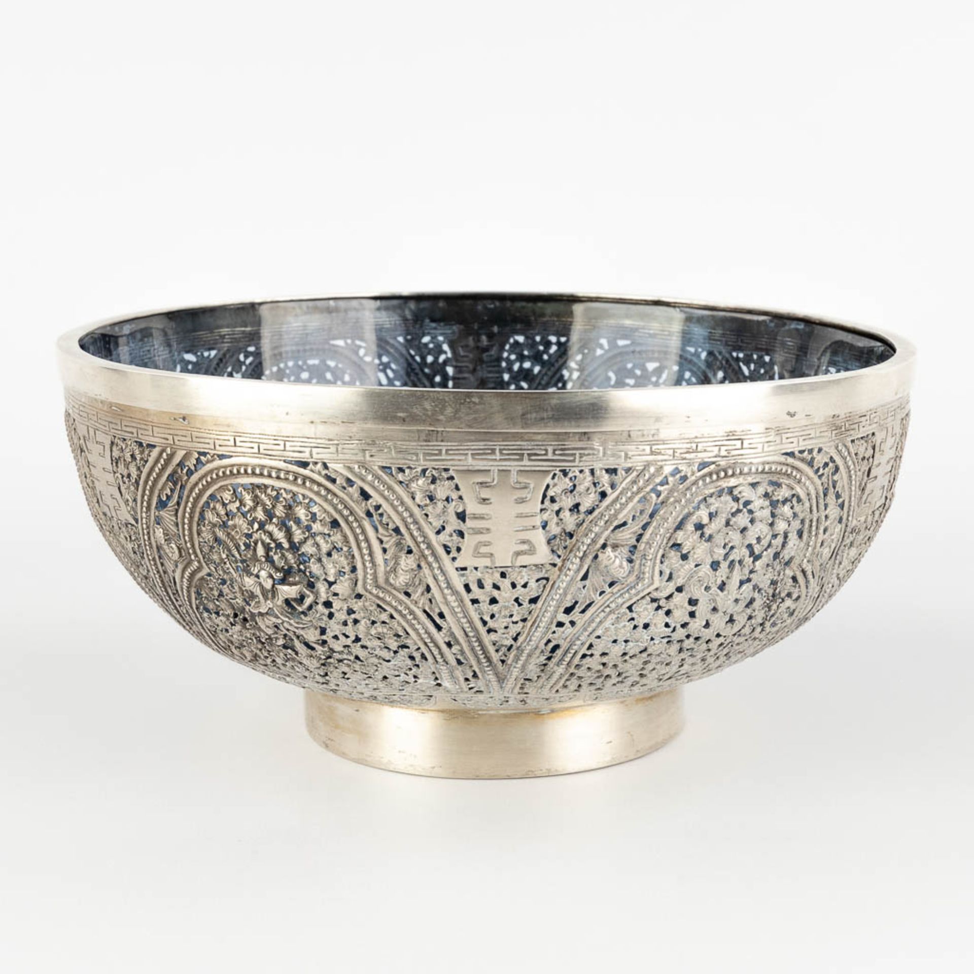 An Asian bowl, silver with a blue glass liner, decorated with bats and lotus flowers. 320g. (H:10 x