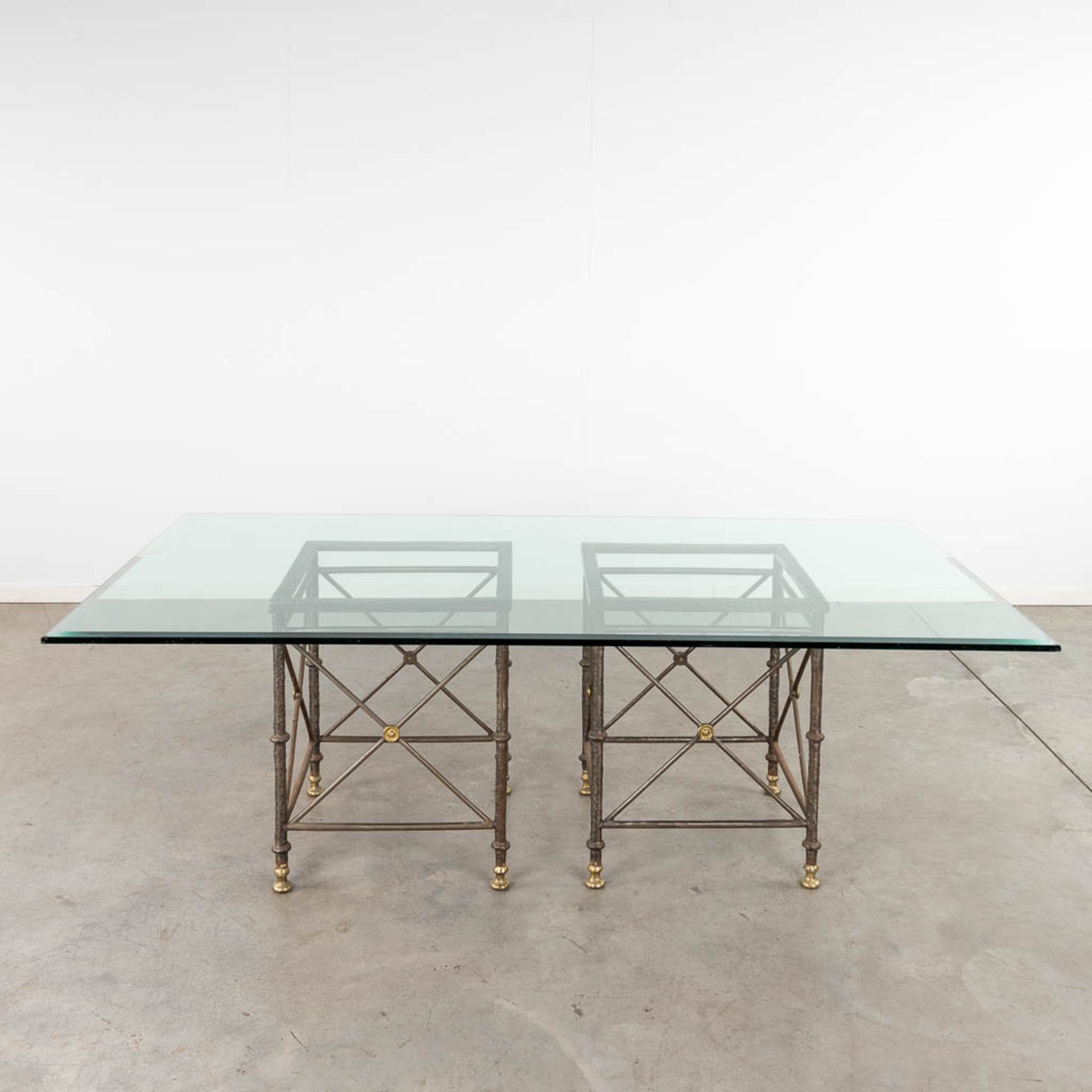 A table with large glass top and a wrought-iron and brass base. (D:120 x W:220 x H:74 cm)