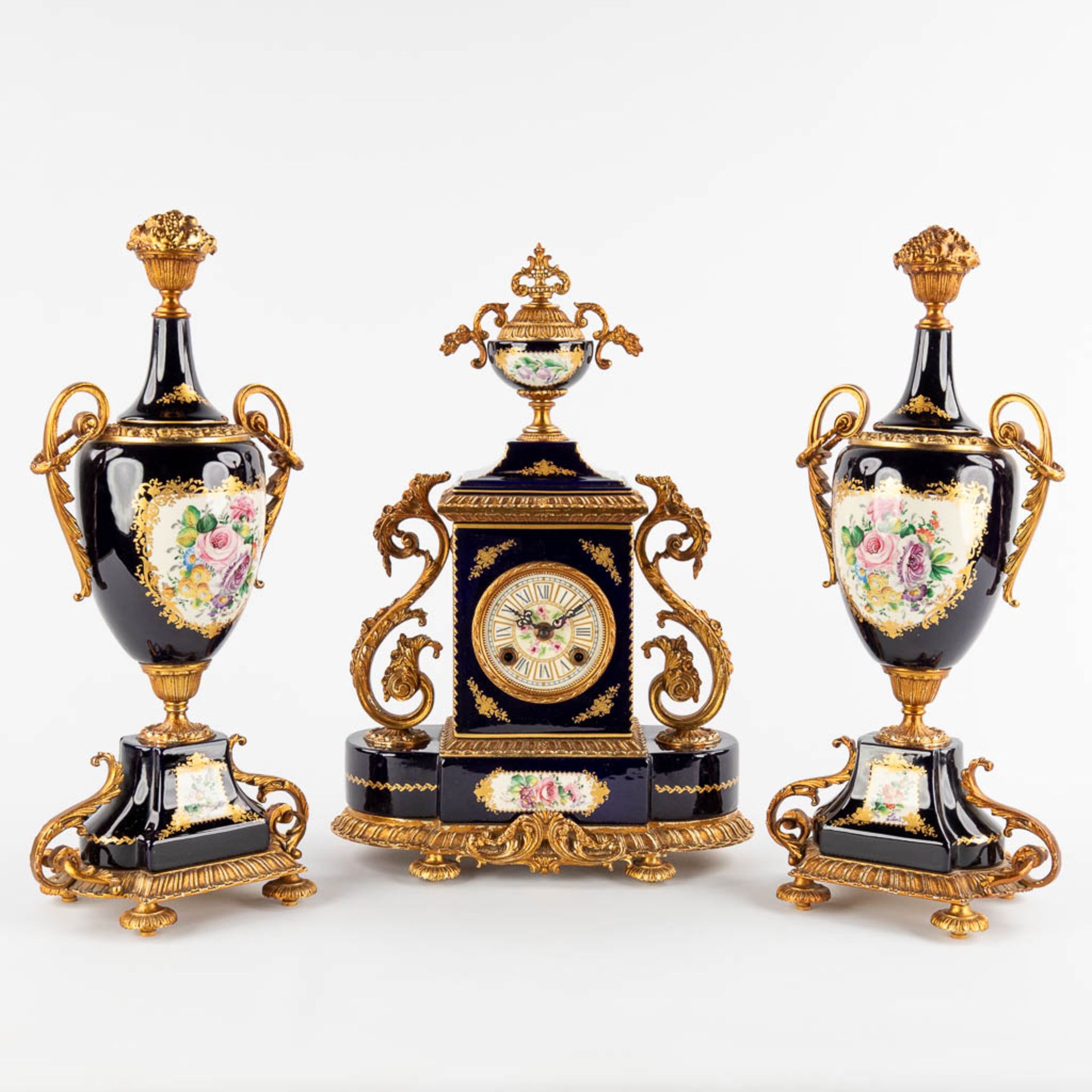 A.C.F. A three-piece mantle garniture clock and side pieces, cobalt blue porcelain mounted with bron