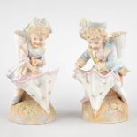 A pair of bisque porcelain figurines of children with an umbrella. 20th C. (D:11 x W:16,5 x H:25 cm)