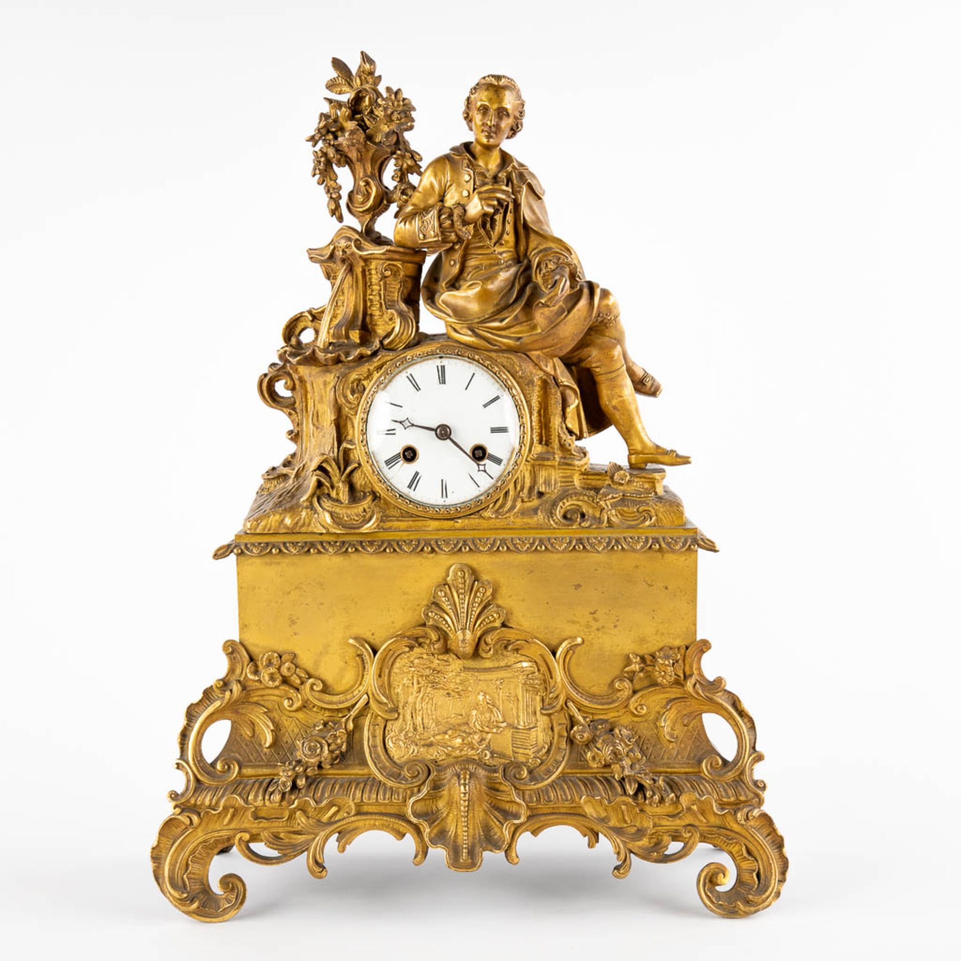 A mantle clock, gilt bronze with an image of a man taking notes. France, 19th C. (D:15 x W:45 x H:38