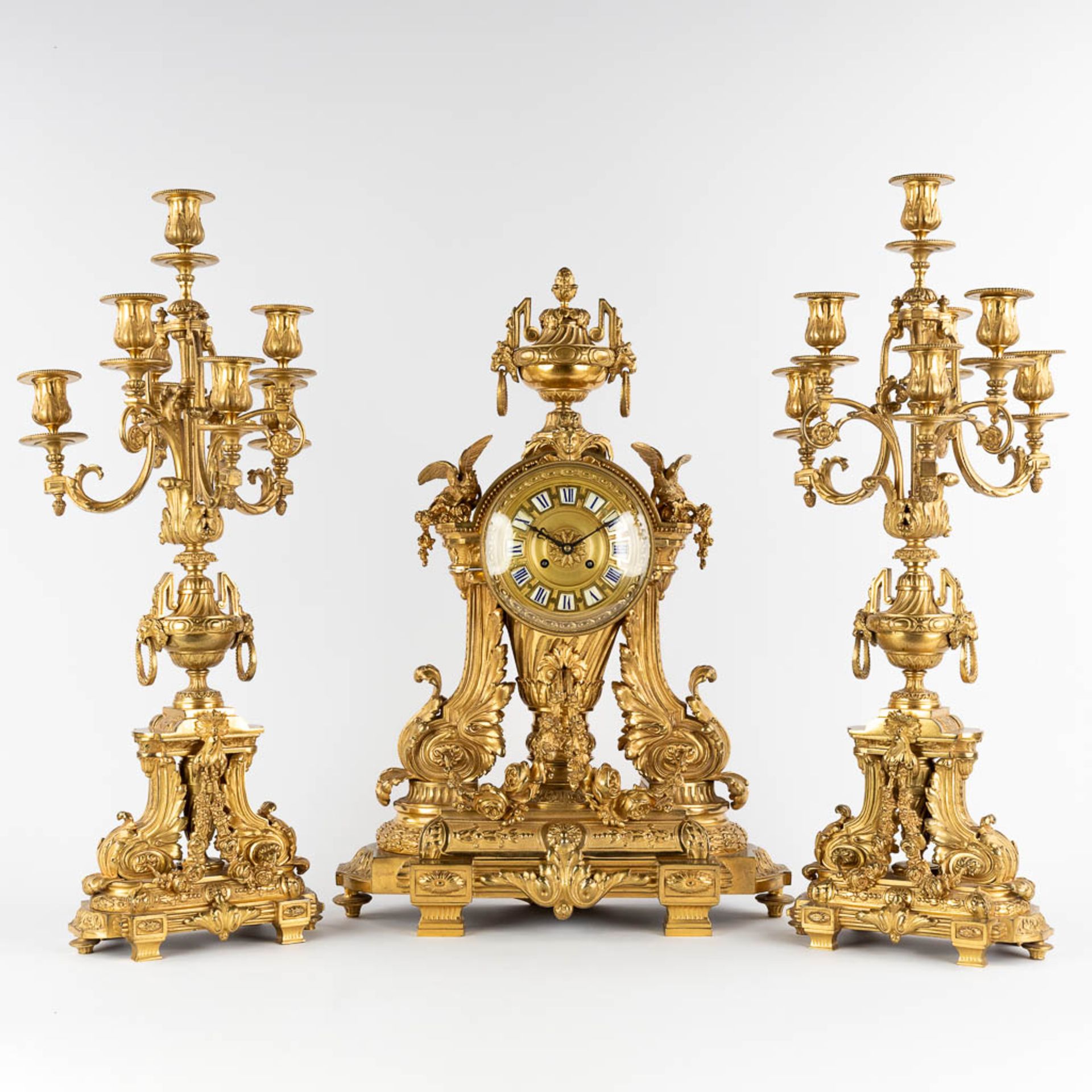 A three-piece mantle garniture clock and candelabra, gilt bronze in a Louis XVI style, 19th C. (D:19