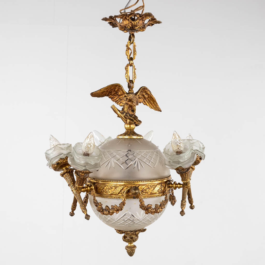 A chandelier, bronze mounted with glass and flambeaux and an eagle in Louis XVI style. (H:60 x D:44 