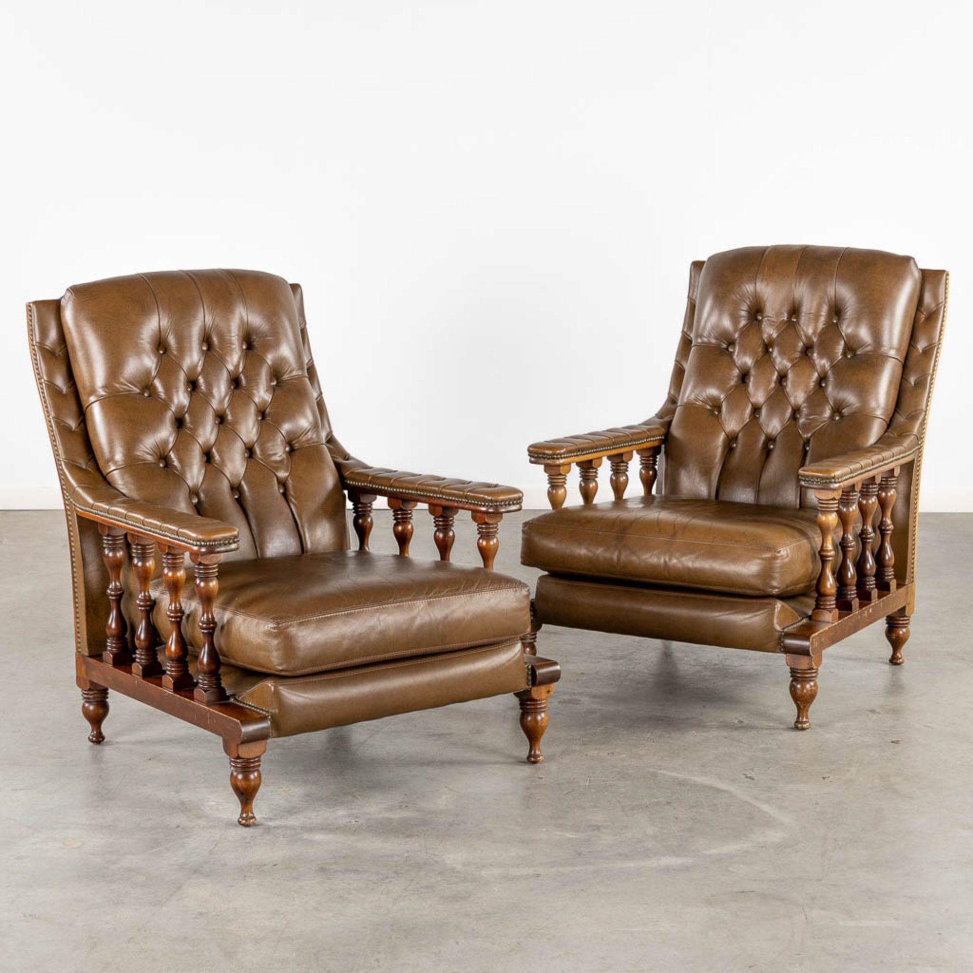 A pair of relax chairs, leather and wood in Chesterfield style. (L:83 x W:74 x H:95 cm)