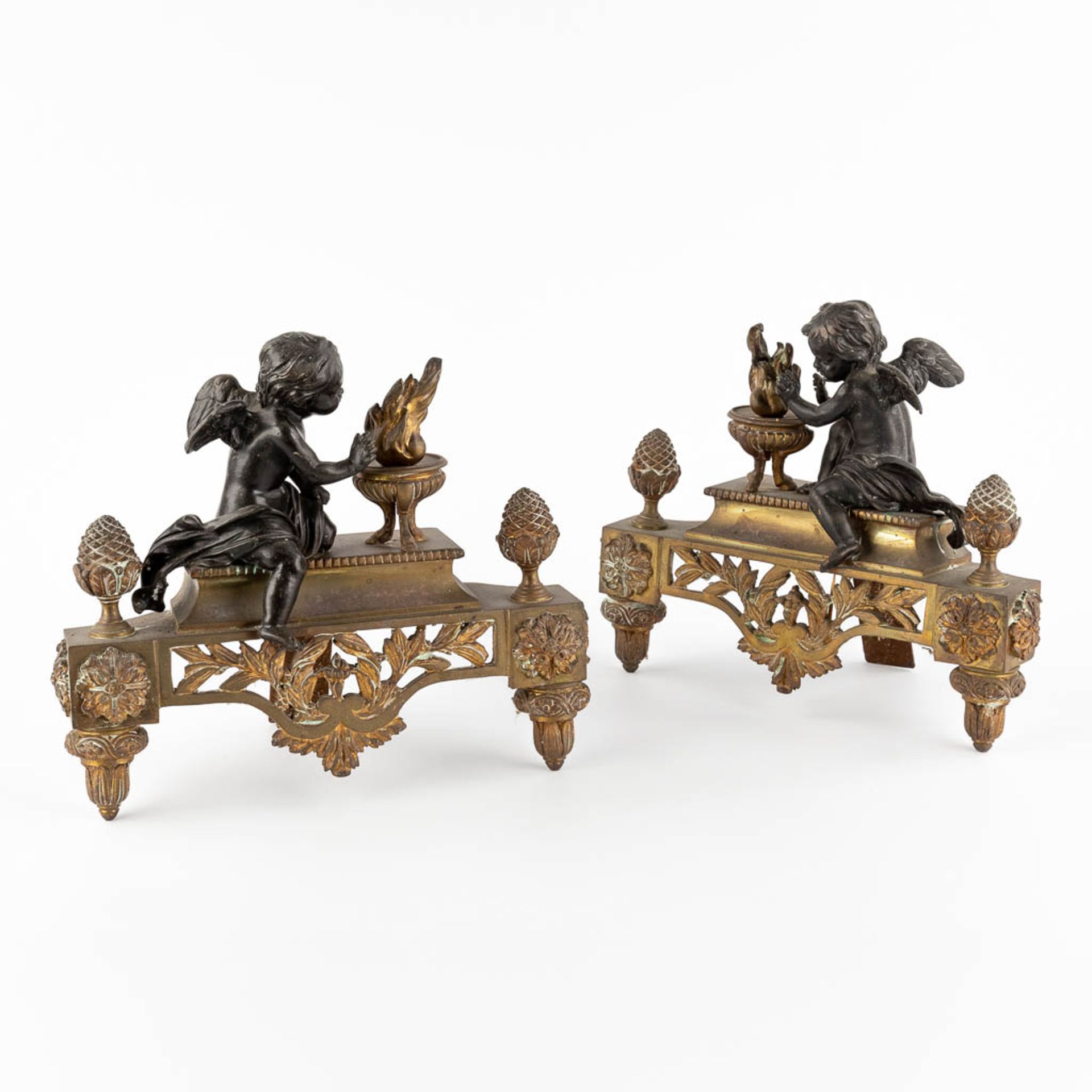 A pair of bronze fireplace andirons, gilt and patinated bronze, Louis XVI style. Circa 1900. (W:30 x
