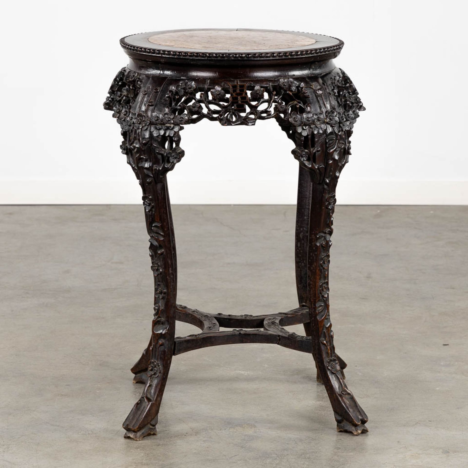 A richly sculptured Chinese hardwood side table or pedestal with a marble. (H:71 x D:53 cm)