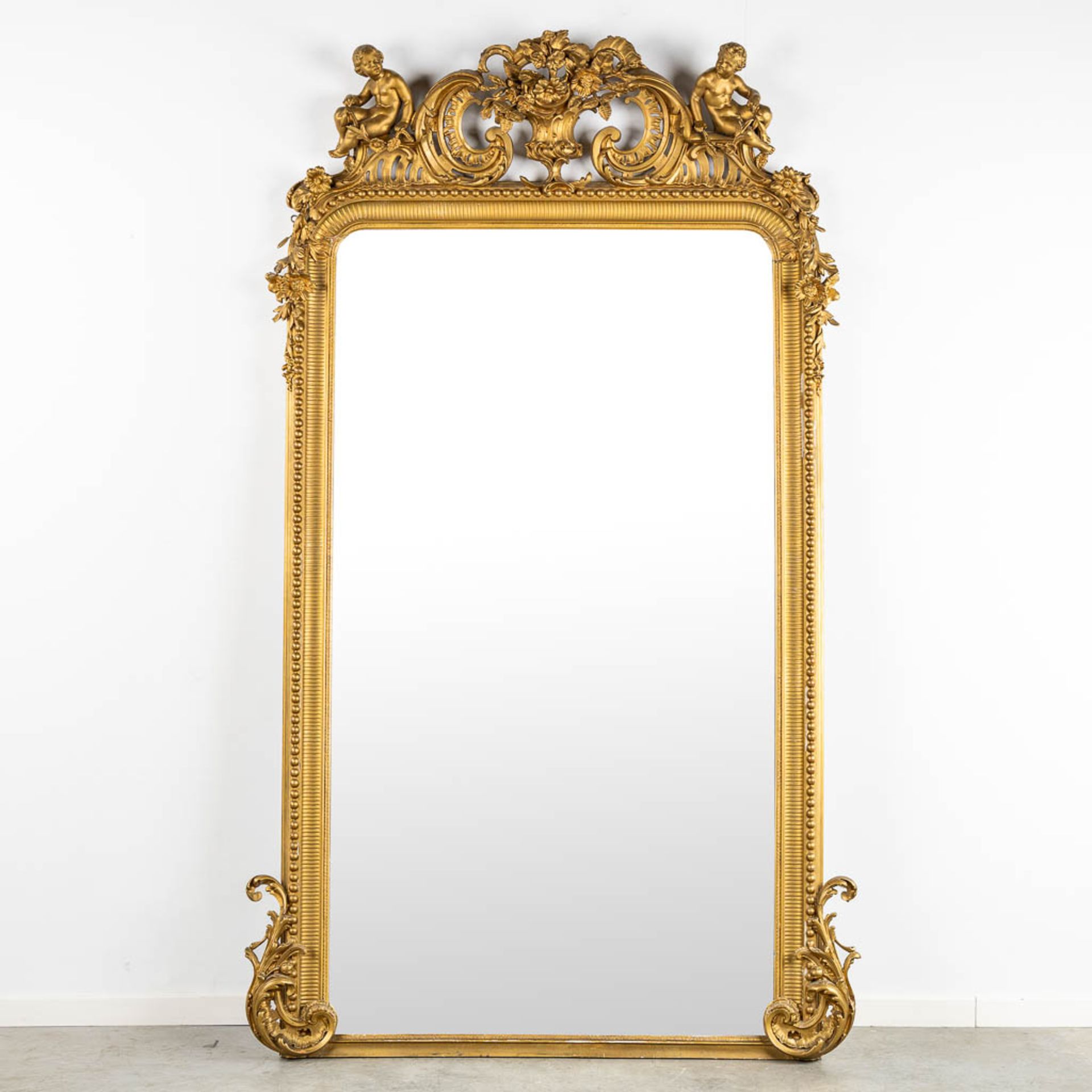 An antique and large mirror, decorated with putti in Louis XV style. Circa 1900. (W:130 x H:225 cm)