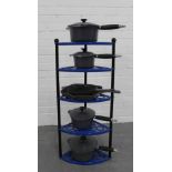 A set of six Le Creuset pots and pans, with a blue metal five tier Le Creuset stand