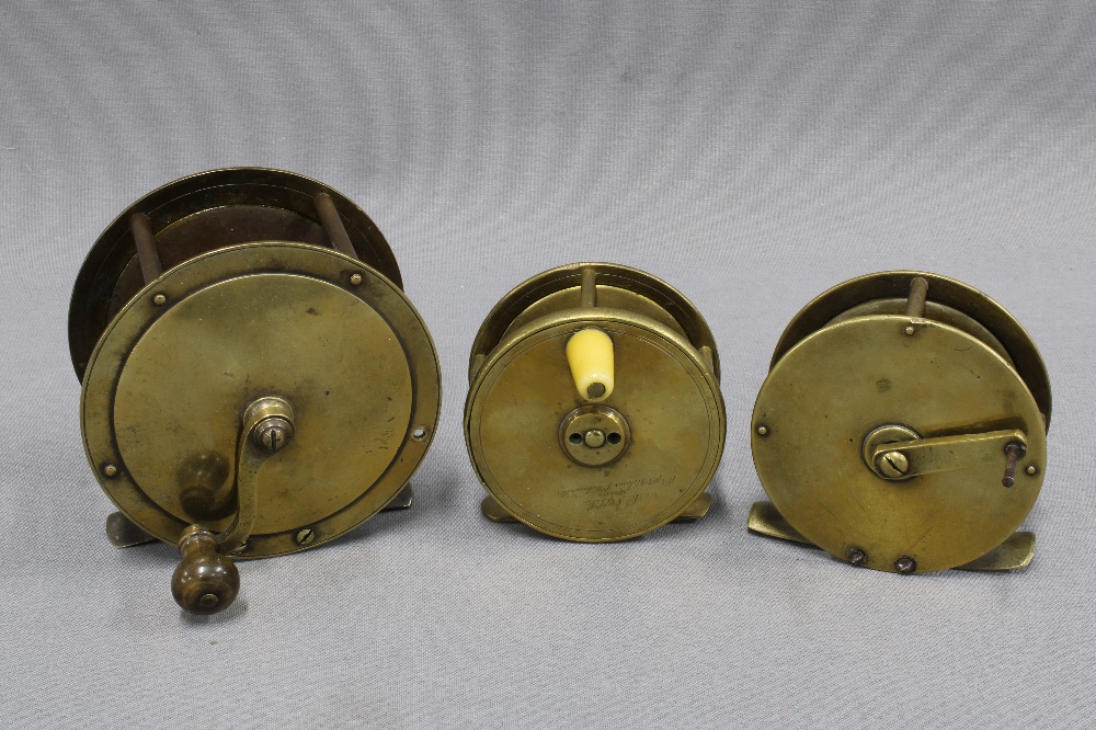 Large brass salmon fishing reel and two smaller brass trout fishing reels, one signed to the