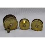 Large brass salmon fishing reel and two smaller brass trout fishing reels, one signed to the