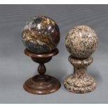 Polished pink granite sphere and pedestal stand together with a polished serpentine hardstone sphere