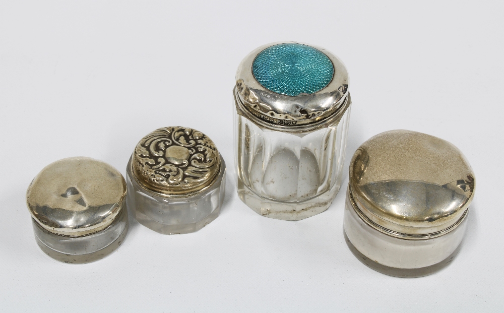 A group of four silver topped glass jars, various hallmarks, tallest 5cm (4)