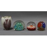 Three coloured glass paperweights and a small art pottery vase (4)