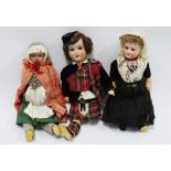 A group of three early 20th century bisque head dolls, one dressed in a Highland outfit, (a/f) (3)
