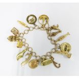9ct gold charm bracelet with a quantity of mainly gold and yellow metal charms to include Statue