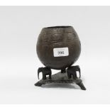 Carved coconut shell on an ebonised stand with elephant supports, 17cm high